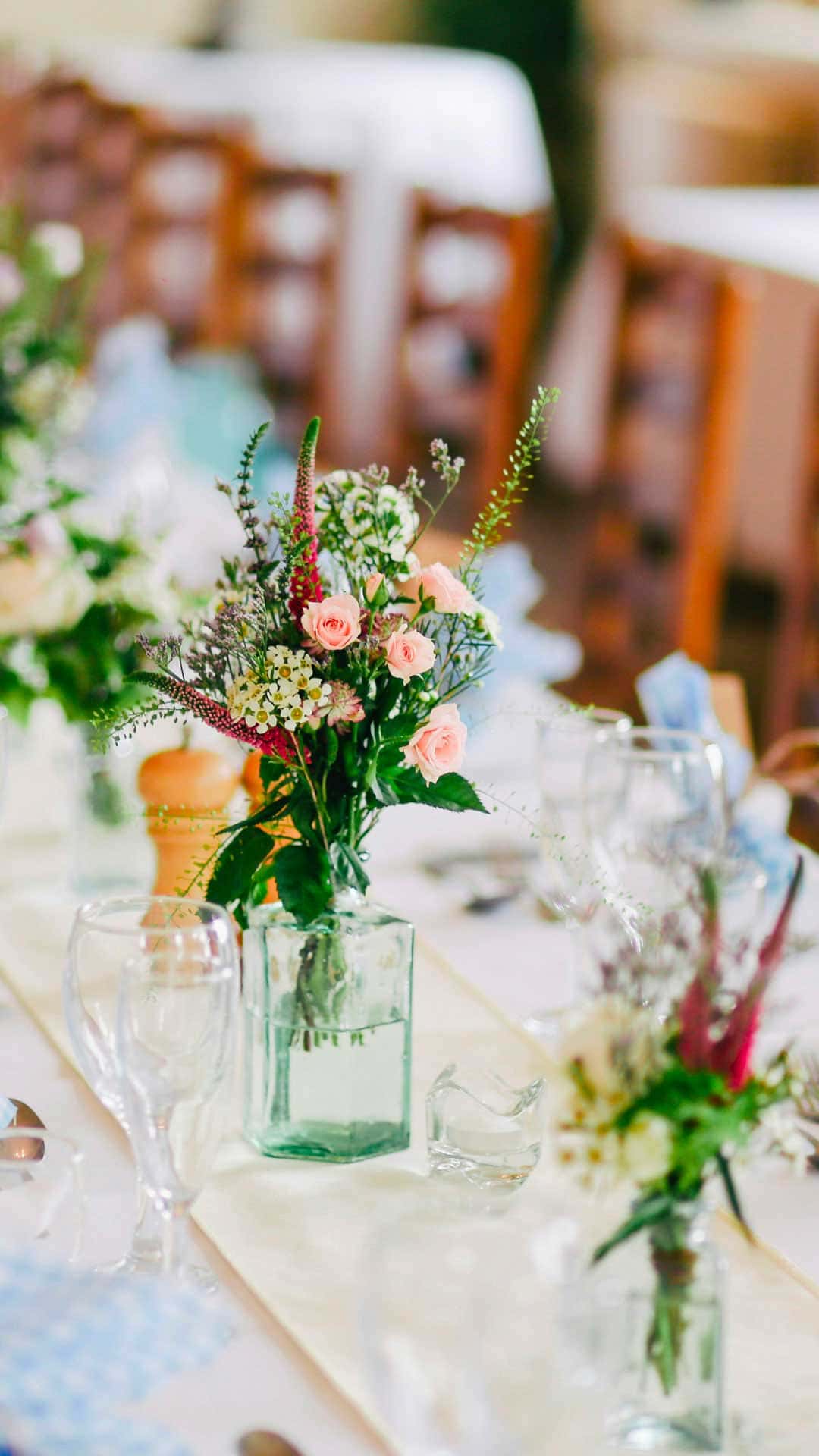 Composizioni floreali rosa e verdi su una tavola di matrimonio